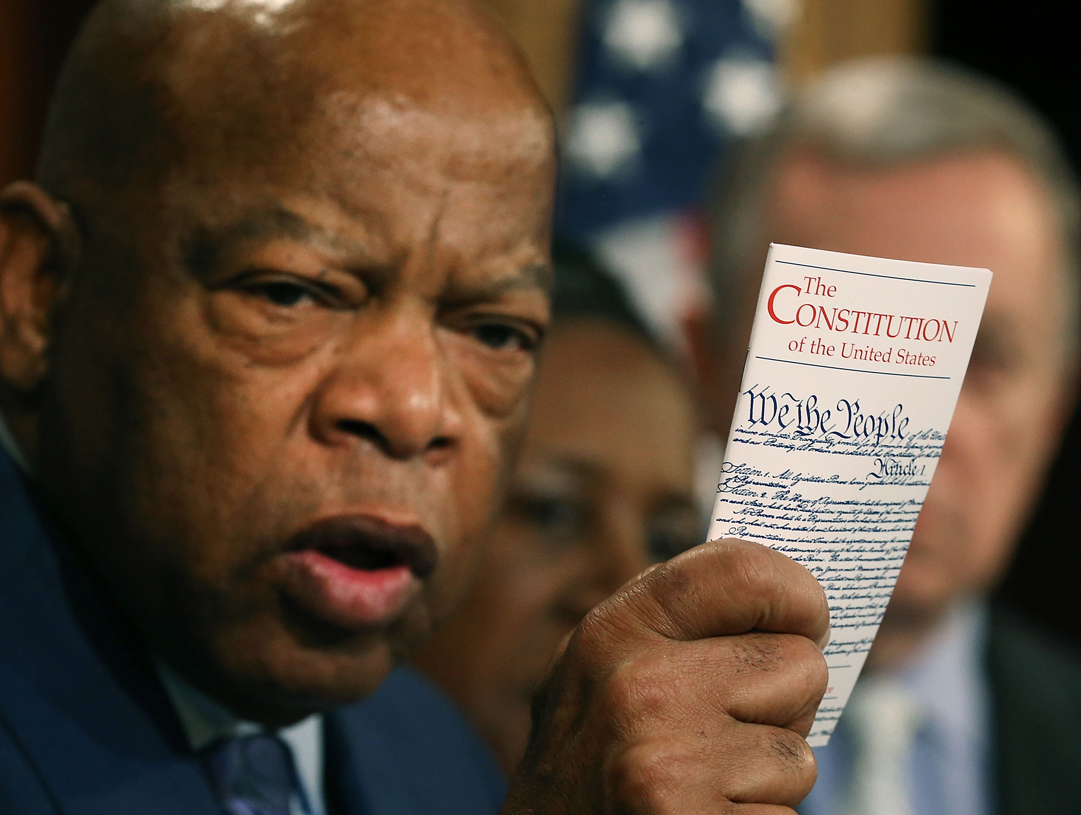 Photograph of John Lewis holding a pocket-sized Constitution, with the Constitution in focus in the foreground