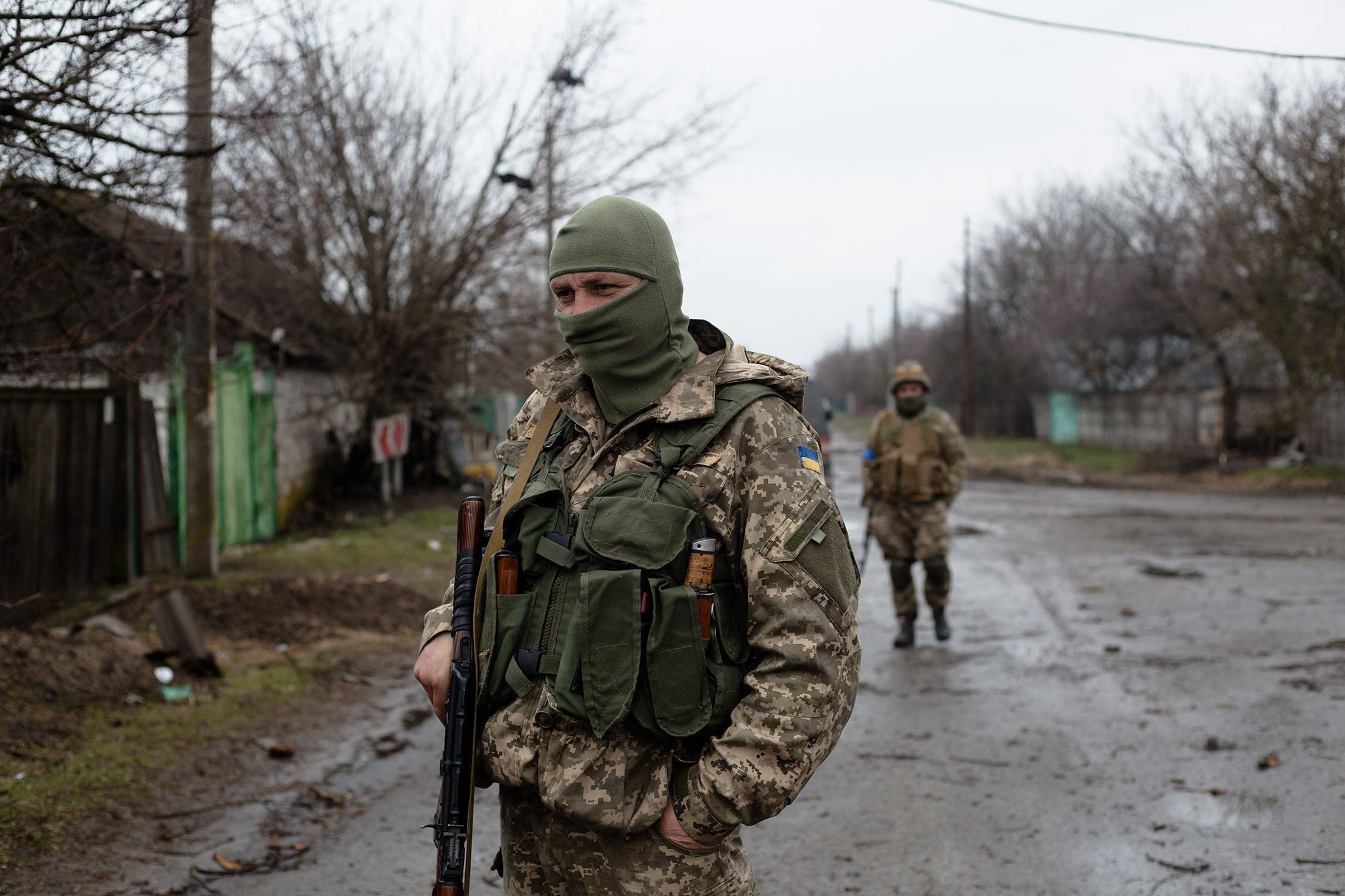 Two men in camouflage uniforms patrol an empty street